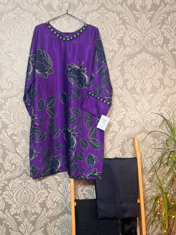 Purple floral-patterned dress with black accents on a hanger against a patterned wall.
