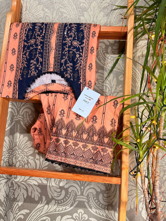 Patterned fabric on a wooden shelf with a plant in the background