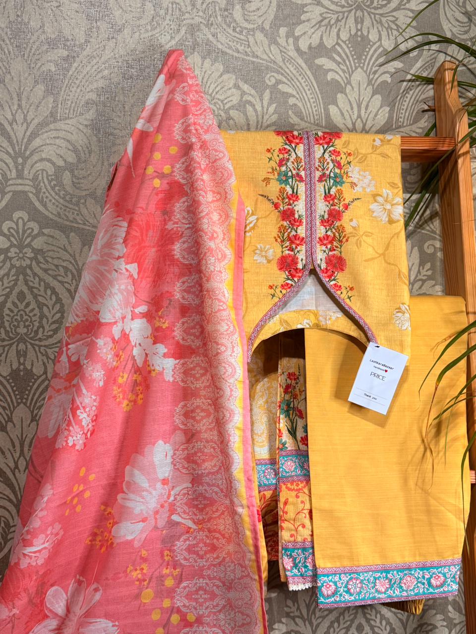 Yellow fabric with floral patterns draped over a chair against a patterned wall.